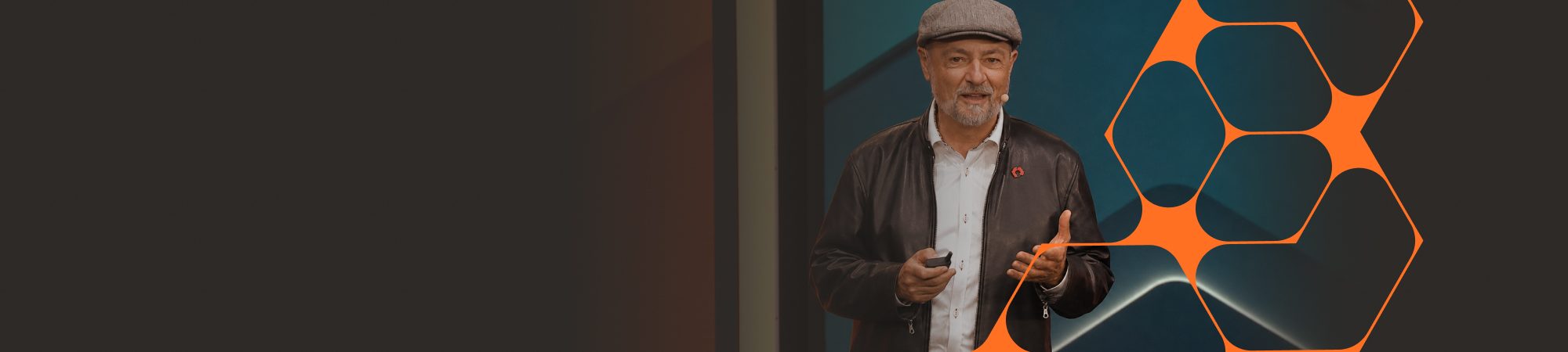 Speaker delivering a presentation against a stylized, geometric backdrop