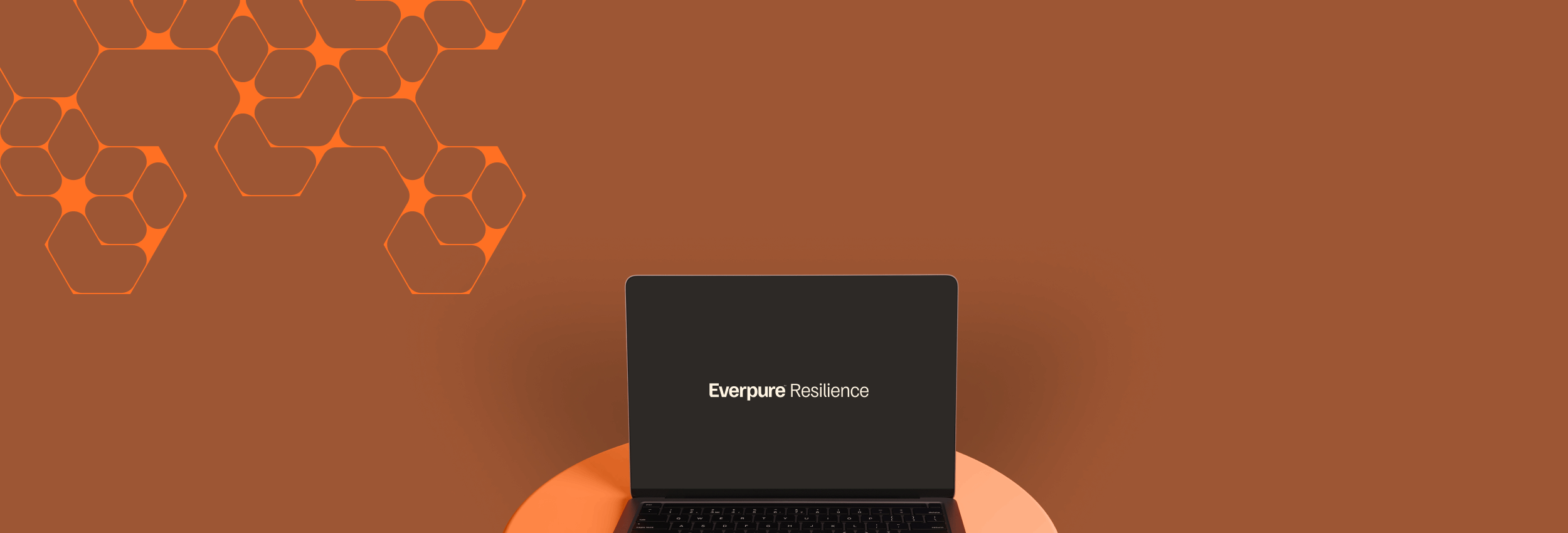 Modern laptop atop a circular surface against a rich orange backdrop featuring geometric designs