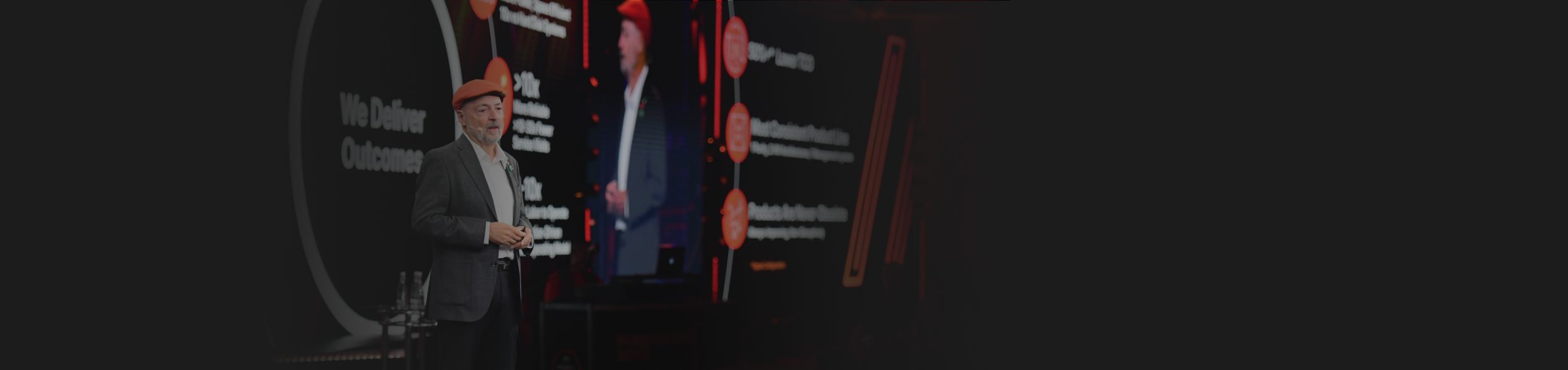 Presenter at a conference sharing insights with a visual display in the background