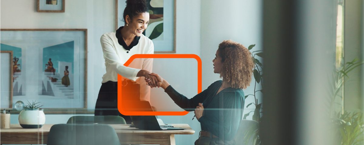 A business meeting where two individuals are shaking hands in a contemporary office environment